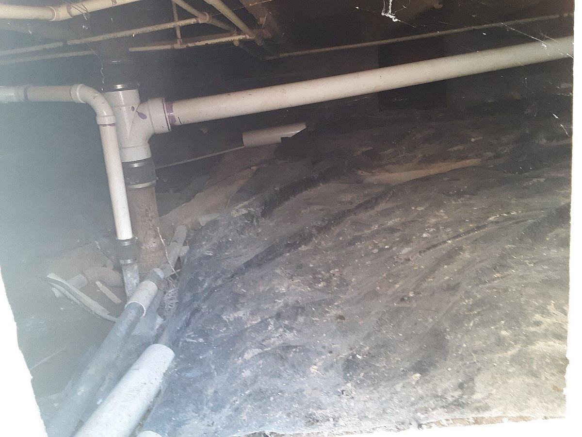Crawl space with vapor barrier and plumbing under a Greensboro-area home